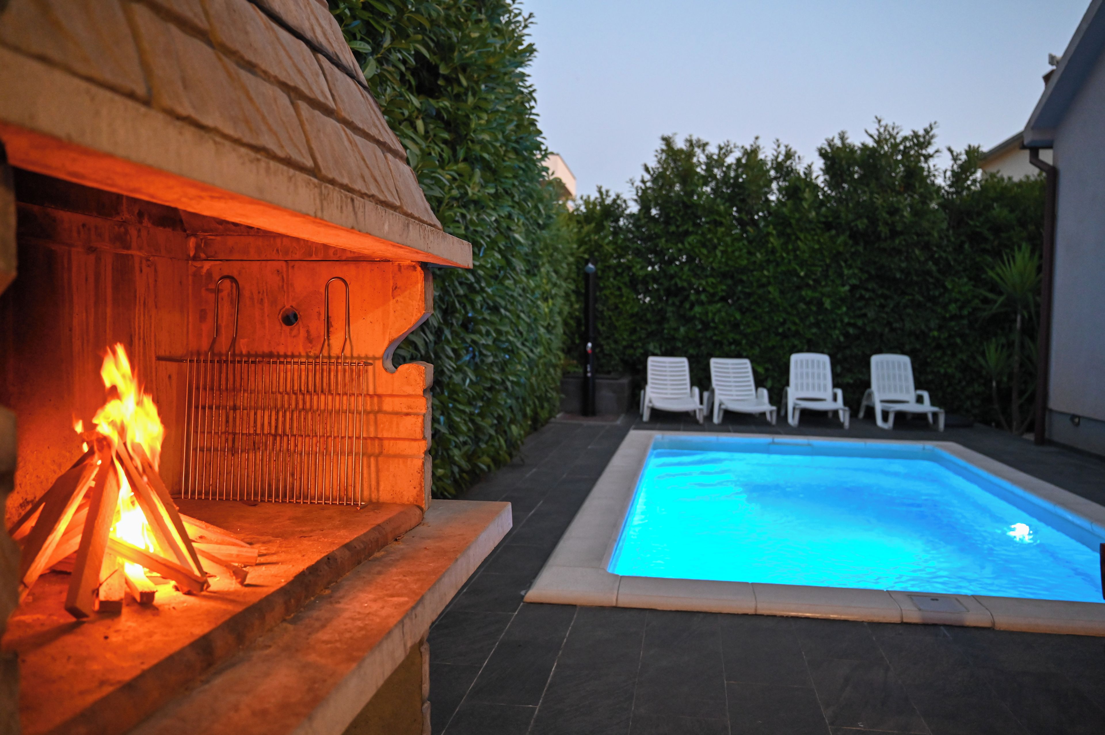Un espace aménagé au bord de la piscine, avec un barbecue et des chaises longues.