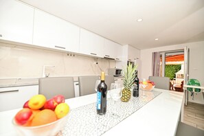 A modern kitchen with white cabinets, a marble countertop, and a dining area with a table set for two. - Holiday home Lucia 5 minutes’ walk from Old Town in Trogir with private pool (Trogir)