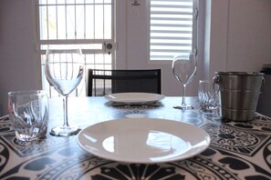 A dining table with a white plate, two wine glasses, and a metal pitcher. - Casa Iliria 2: cozy 1-bedroom apartment with AC in charming Boquerón (Boquerón)