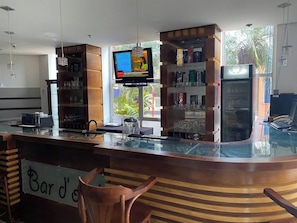 A bar area with a sign reading 'Bar d'o', shelves with glasses, a television screen, and a view of greenery outside. - Quality Hotel Sao Carlos (São Carlos)