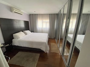 A hotel room with a large bed, a bedside table, an air conditioning unit, and a sliding glass door leading to another room. - Quality Hotel Sao Carlos (São Carlos)