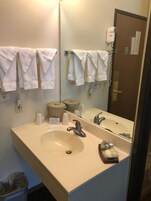 Un baño con lavamanos, espejo, toallero y secador de pelo.