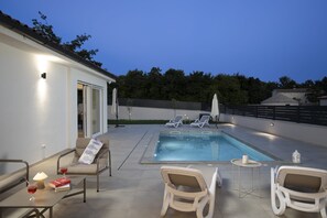 An outdoor swimming pool area with lounge chairs, a table with a drink, and a book. - Casa Zucchero (Cukrići)