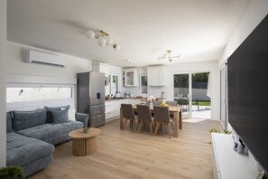 Een moderne woonruimte met een bank, eettafel en keukenhoek.