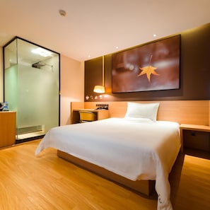 A hotel room with a large bed, a desk with a chair, a glass shower enclosure, and a wall-mounted artwork. - Iu Hotel Shanghai Minhang Jiaotong University Dongchuan Road Subway Station Branch (Shanghai)