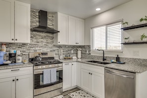 A modern kitchen with white cabinets, a stainless steel stove, and a tiled backsplash. - Desert Oasis: Home Near Joshua Tree NP! (Twentynine Palms)