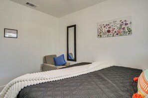 A bedroom with a bed, a chair, a mirror, and a floral artwork on the wall. - Desert Oasis: Home Near Joshua Tree NP! (Twentynine Palms)