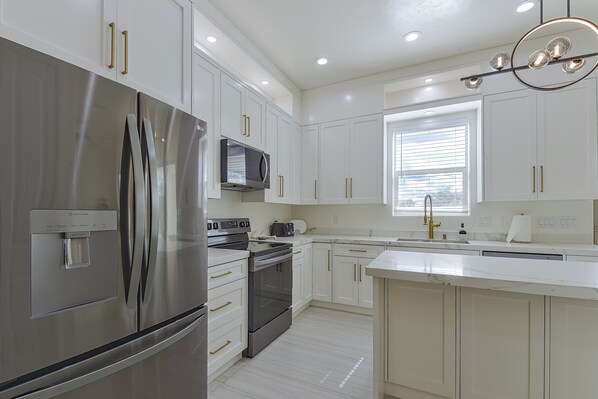 A modern kitchen with stainless steel appliances, white cabinetry, and a central island. - Modern Rio Rico Home Near Nogales & Lake Rec! (Rio Rico)