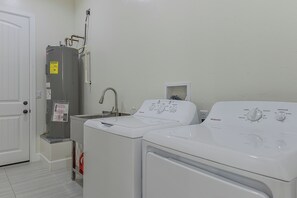 A laundry area with two washing machines, a water heater, and a wall-mounted sink. - Modern Rio Rico Home Near Nogales & Lake Rec! (Rio Rico)