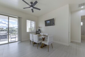 A dining area with a ceiling fan, a flat-screen TV mounted on the wall, and a dining table set for four. - Modern Rio Rico Home Near Nogales & Lake Rec! (Rio Rico)