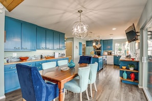 Eine moderne Küche mit blauen Schränken, einem Holztisch und einem außergewöhnlichen Kronleuchter.