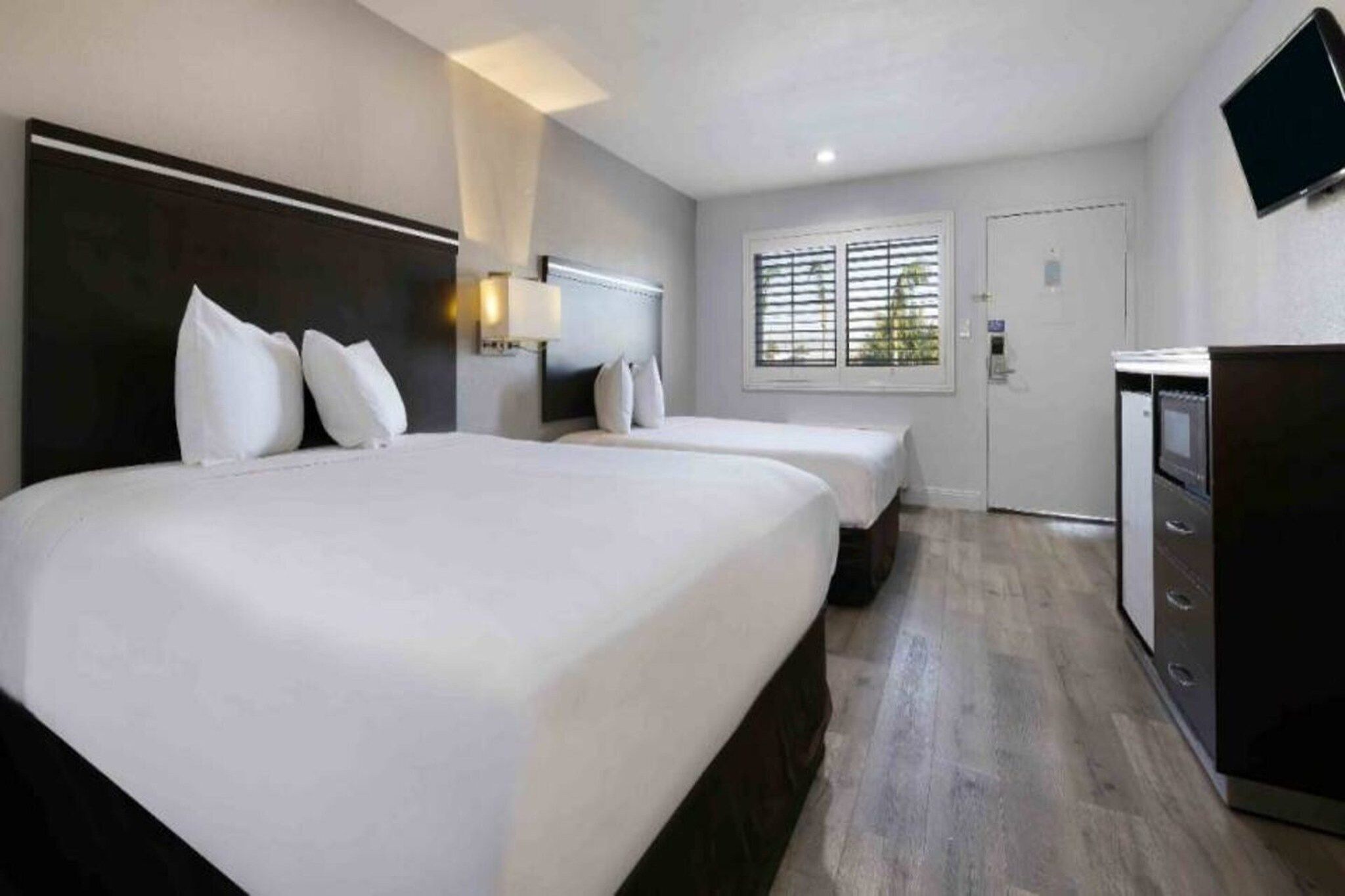 A hotel room with two beds, a TV, and a desk.
