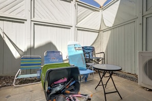 A covered outdoor area with a seating arrangement including chairs and a table, a storage unit with various items, and a fan. - Welcome to Paradise, Perfect Getaway (Kihei)