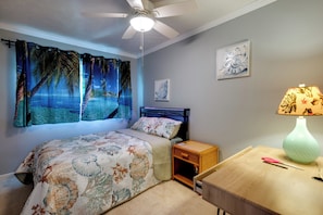 A bedroom with a bed, a nightstand, a lamp, a ceiling fan, and a wall with a painting. - Welcome to Paradise, Perfect Getaway (Kihei)
