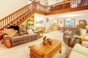 A spacious living area with a wooden staircase, a dining table with chairs, and a kitchen area. - Northwoods Home on a Private No-Motor Lake (Lakewood)