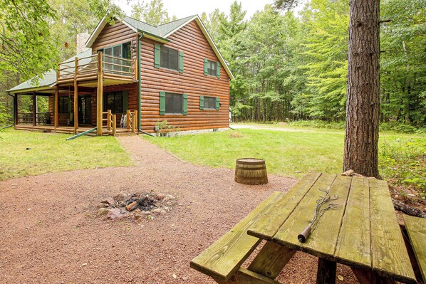 A rustic log cabin with a porch, a fire pit, and a picnic table. - Northwoods Home on a Private No-Motor Lake (Lakewood)