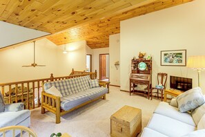 A cozy living room with a wooden ceiling, a checkered sofa, a television, and a fireplace. - Northwoods Home on a Private No-Motor Lake (Lakewood)