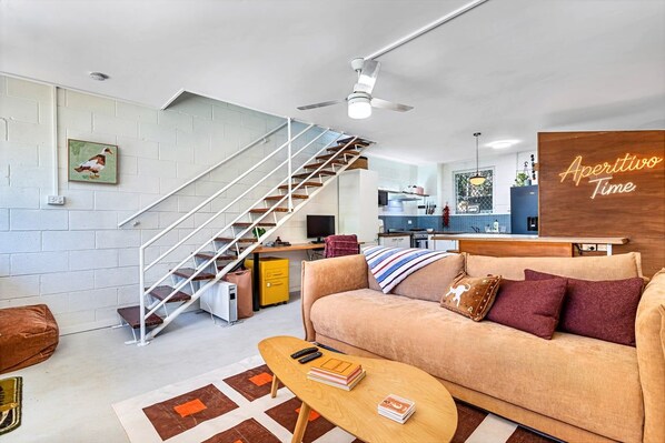 Ein zeitgemäßer Wohnraum mit Treppe, einer Couch, einem Couchtisch und einer Küchenzeile.