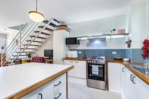 Eine moderne Küche mit einer zentralen Kochinsel, einem eingebauten Mikrowellenherd, Backofen und einer Treppe, die zu einer anderen Ebene führt.