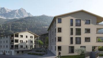 A multi-story residential building with a flat roof, large windows, and a paved courtyard.