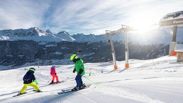 Skifahrer auf einem verschneiten Hang mit Bergblick und einer Seilbahn in der Ferne.