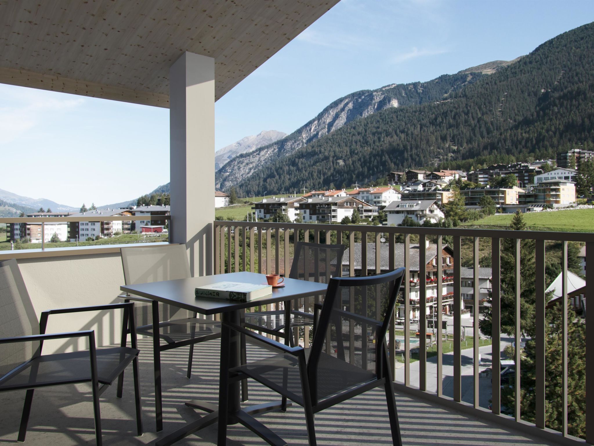 Varanda com mesa e cadeiras, com vista para uma paisagem montanhosa com edifícios.