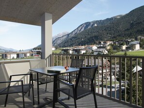 A balcony with a table and chairs, overlooking a mountainous landscape with buildings. - Residenza Grava Appartement/Fewo, Dusche, WC, 1 Schlafraum by Interhome (Savognin)