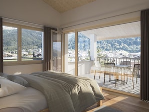 A bedroom with a large bed, a balcony with a table and chairs, and a view of a mountainous landscape. - Residenza Grava Appartement/Fewo, Dusche, WC, 1 Schlafraum by Interhome (Savognin)
