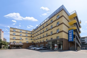 A hotel building with multiple floors, a flat roof, and a parking lot in front. - Homeinn (Beijing)