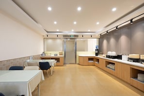 A modern kitchen area with a dining table and chairs, a counter with appliances, and a glass door entrance. - Homeinn (Beijing)