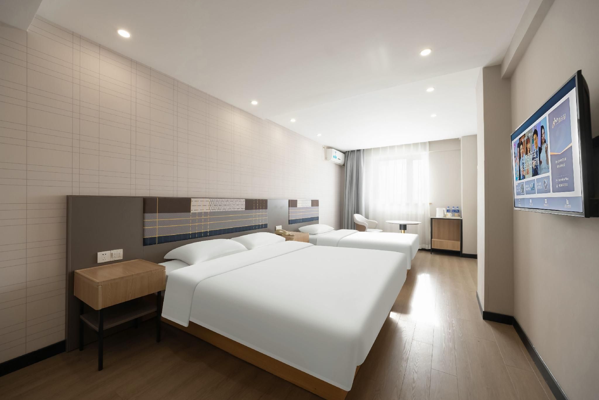 Ein Hotelzimmer mit zwei Betten, einem Schreibtisch, einem Stuhl, einem Fernseher und einem Fenster mit Vorhängen.