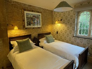 A room with two beds, a painting, and a window with a view.