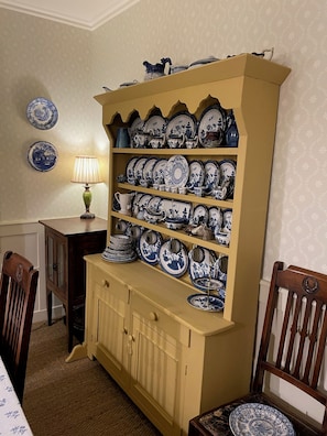 Un comedor con un mueble de madera lleno de platos y tazones azules y blancos.
