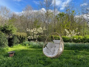 A garden with a hanging chair and a bird bath.