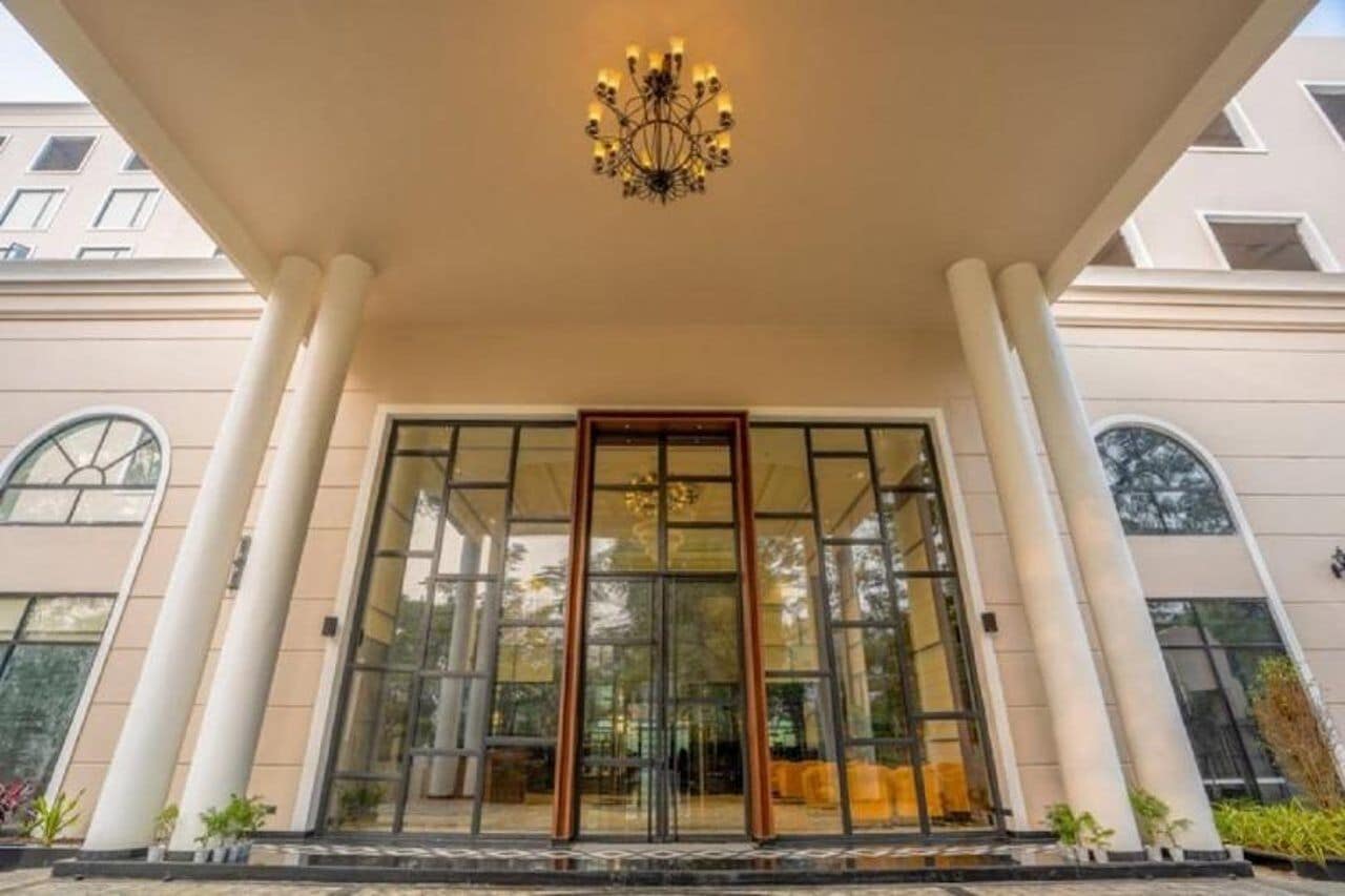 A hotel entrance with a glass door, columns, and a chandelier.