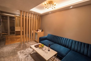 A modern living room with a blue sofa, a coffee table with fruits and a bottle, and a wooden partition. - Polo Hotels, Agartala (Agartala)