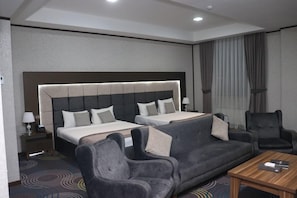 A hotel room with two beds, a sofa, a coffee table, and a chair. - Volga Hotel Baku (Baku)