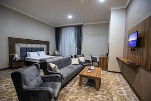 A hotel room with a bed, sofa, armchair, coffee table, TV, and a small desk. - Volga Hotel Baku (Baku)