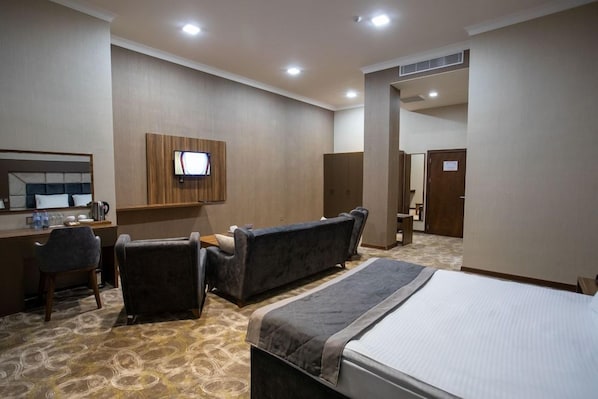 A hotel room with a bed, two sofas, a desk, a television, and a bathroom. - Volga Hotel Baku (Baku)