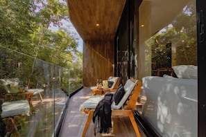 A modern outdoor lounge area with wooden flooring, glass balustrades, and seating arrangements. - Xambe Tulum (Tulum)