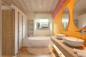 A modern bathroom with a freestanding bathtub, two vessel sinks, and a large mirror. - Mastrojanni Relais (Montalcino)