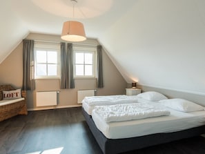 A bedroom with a loft bed, a bedside table with a lamp, and a window with curtains. - Charming Villa in the Dunes of Ameland for 8 (Nes)