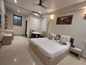 A modern bedroom with a large bed, bedside tables, a desk, and a chair. - Hotel Downtown (Rajkishore Nagar)