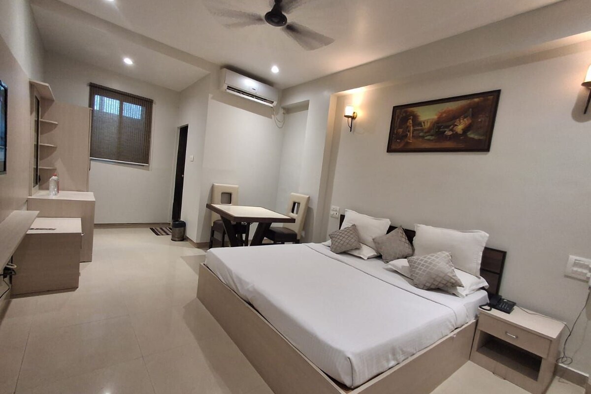 A modern bedroom with a large bed, bedside tables, a desk, and a chair.