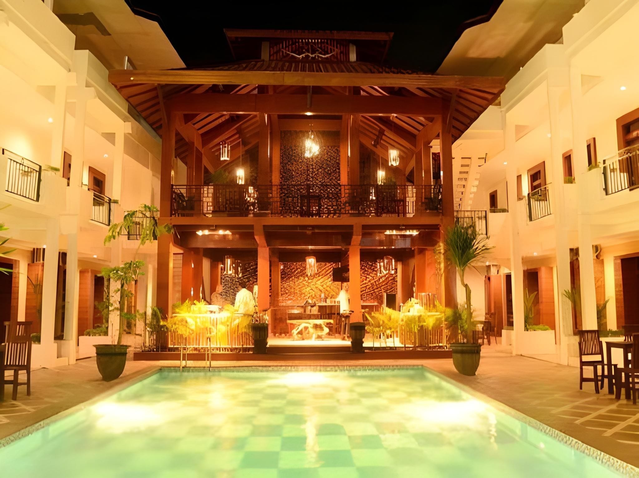 A hotel courtyard with a pool, outdoor seating, and a decorative fountain.