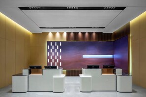 A reception area with a modern design, featuring a reception desk, a wall-mounted screen, and a patterned wall. - Ramada by Wyndham Khorgos Free Trade Zone (Lianyungang)