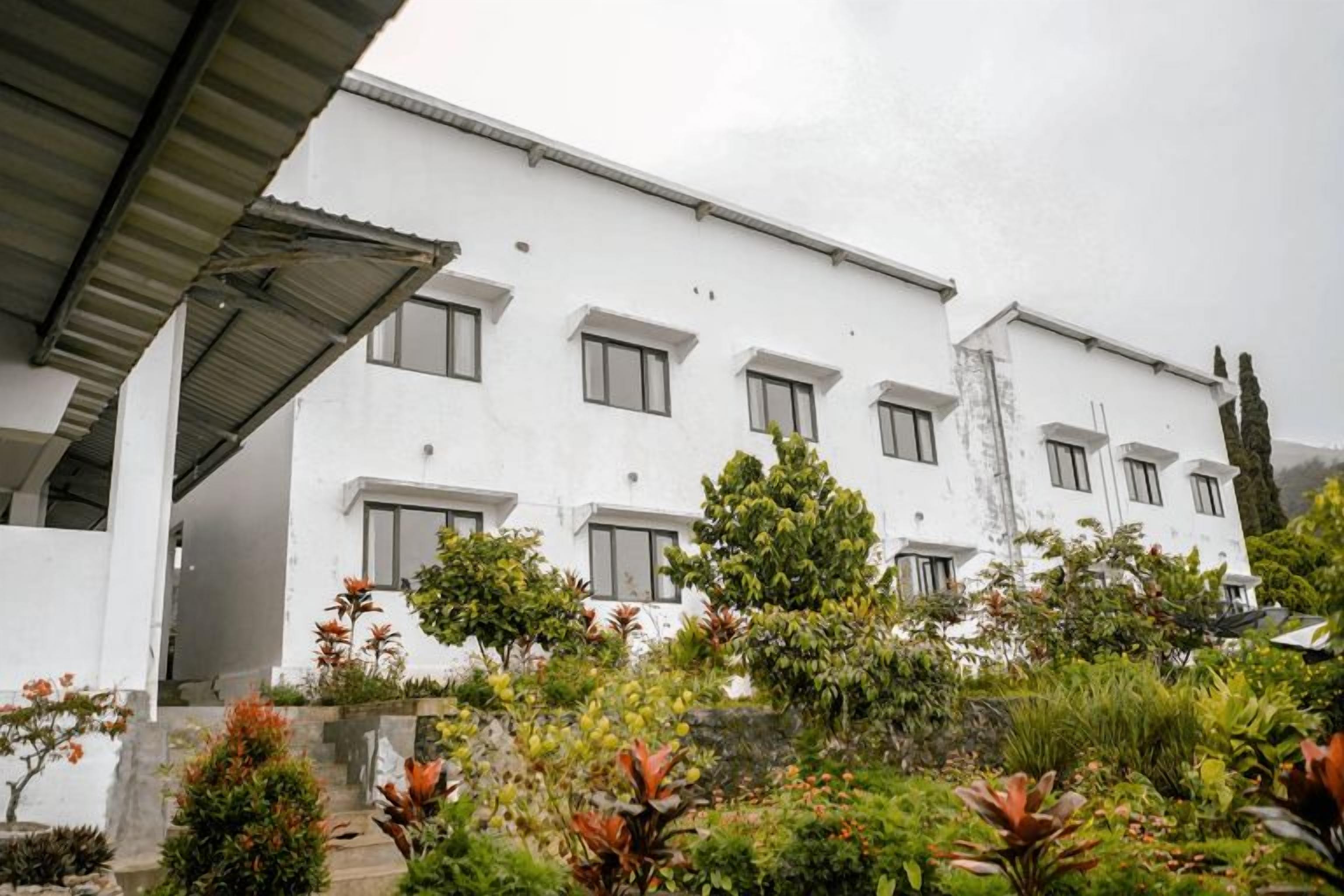 Un bâtiment blanc doté de nombreuses fenêtres et d’une entrée abritée.