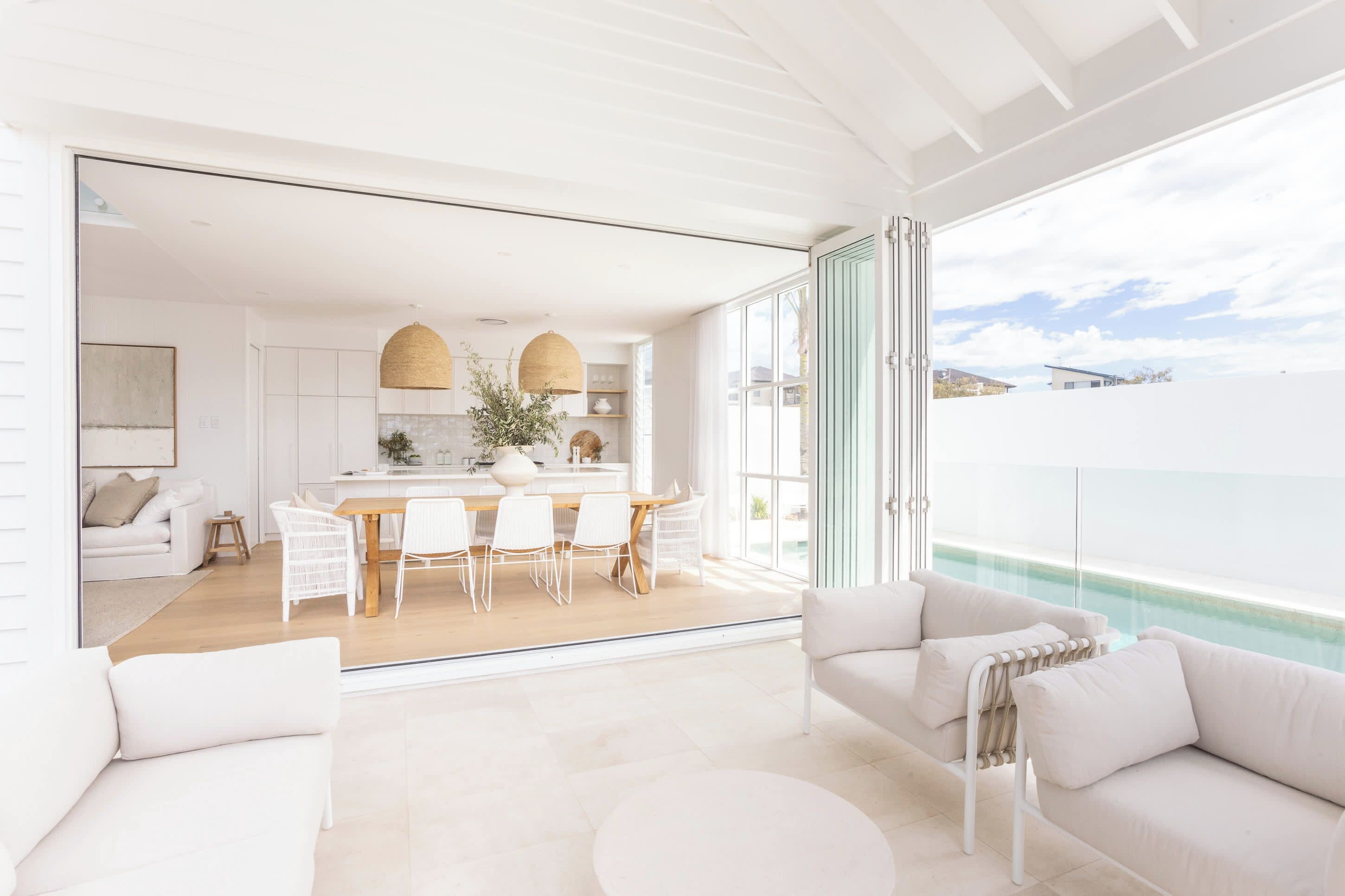 A modern interior with a dining area, kitchen, and a balcony with a pool.
