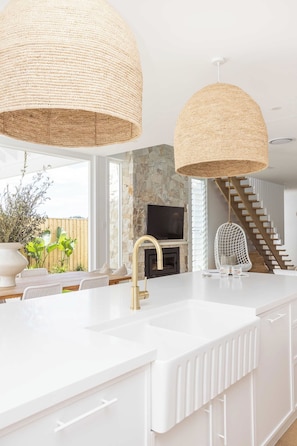 A modern kitchen with a white countertop, gold faucet, and woven pendant lights. - Bianca dal Mare- Stunning Beachside Retreat in Casuarina (Casuarina)