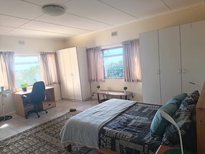 A bedroom with a bed, a desk, a chair, a wardrobe, and a window with curtains. - Mountain Side Golden gem (Cape Town)